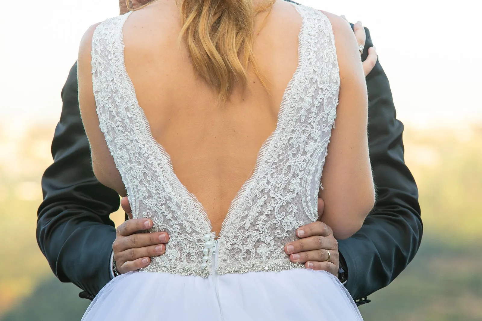 Close-up of a bride and groom embracing outdoors in a romantic setting.